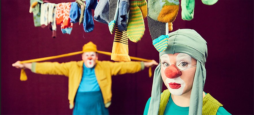 Bild. Två clowner under en tvättlina med kläder.