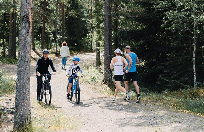 Cyklister och joggare på en skogsstig.