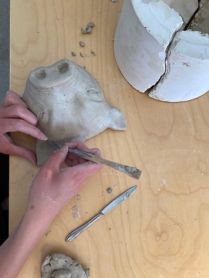 En elev skapar ett grishuvud av lera.